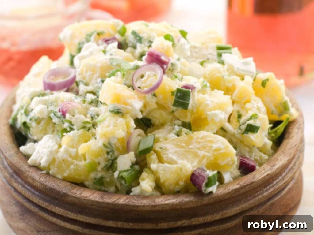 Creamy potato salad garnished with red onions an scallions in a brown bowl.