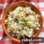 Southern coleslaw with vinegar dressing in a brown bowl on top of a red checkered cloth.