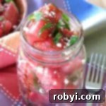 Watermelon Basil Feta Salad in a mason jar with a fork next to it.