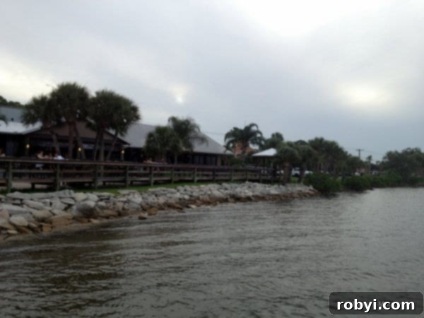 Panoramic view of the River Rocks Restaurant situated along the water's edge, featuring a very long bar running parallel to the rocks, perfect for enjoying waterfront dining.