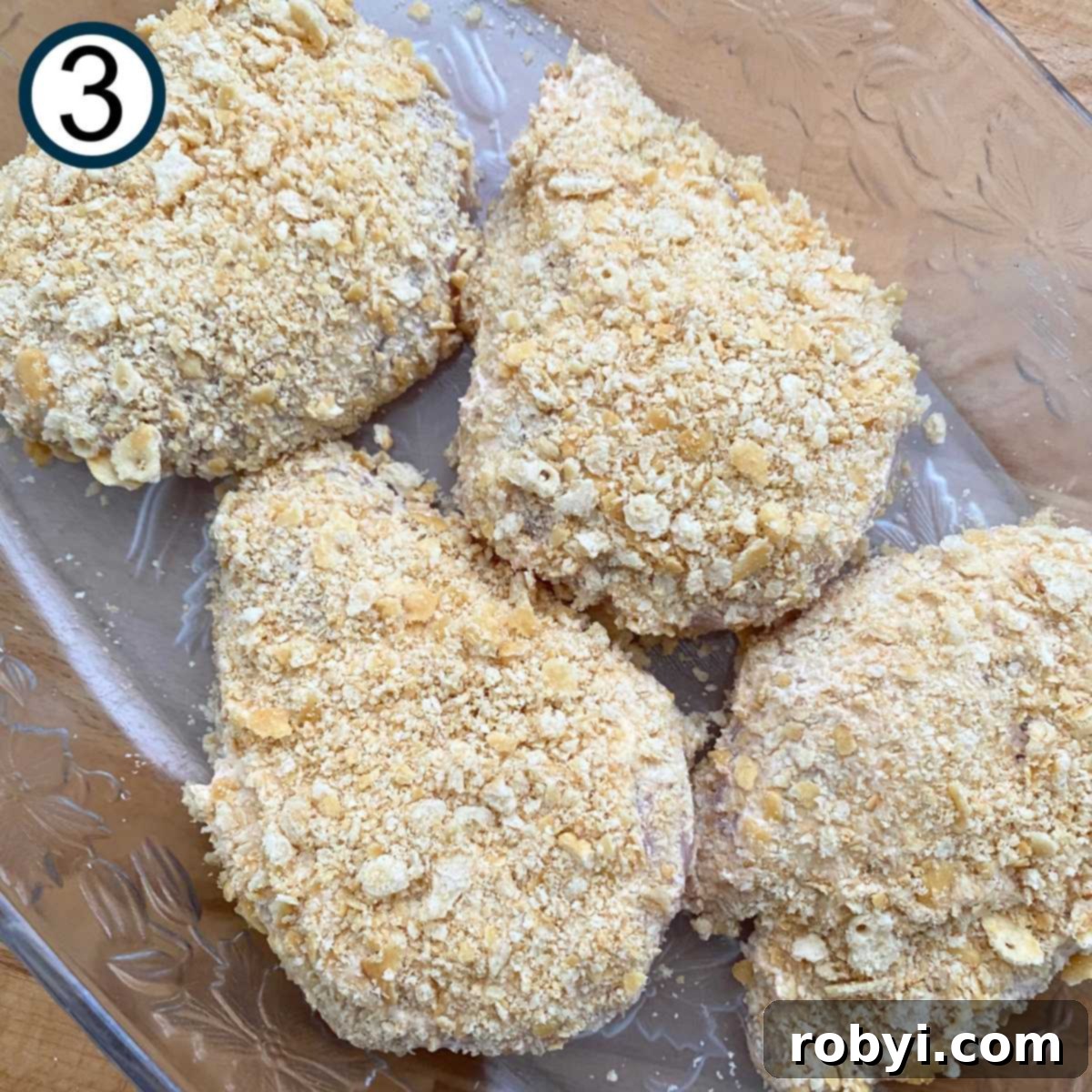 Crispy Ritz Cracker Chicken Perfection 6 Uncooked chicken breasts with a Ritz cracker topping in a glass baking dish.