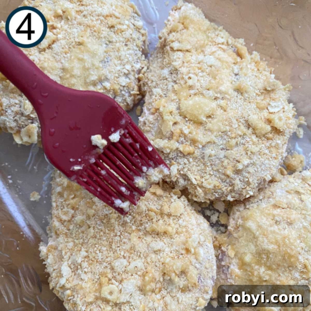 Crispy Ritz Cracker Chicken Perfection 7 Melted butter being brushed over Ritz cracker crumb chicken in a glass baking dish.