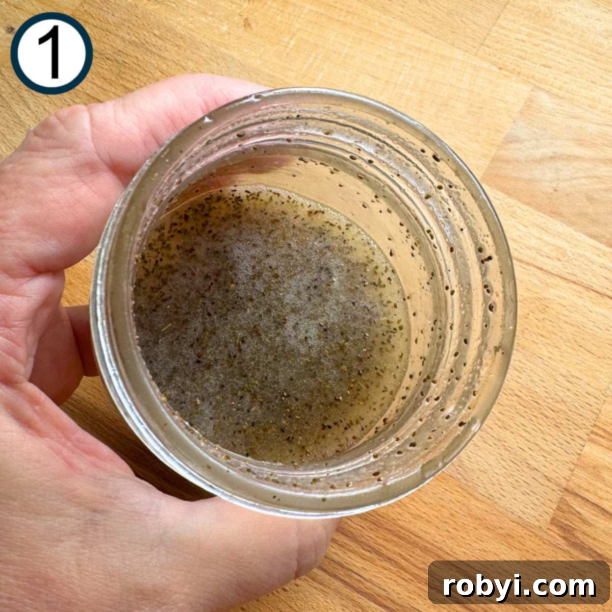 Hand holding a jar with coleslaw vinaigrette.