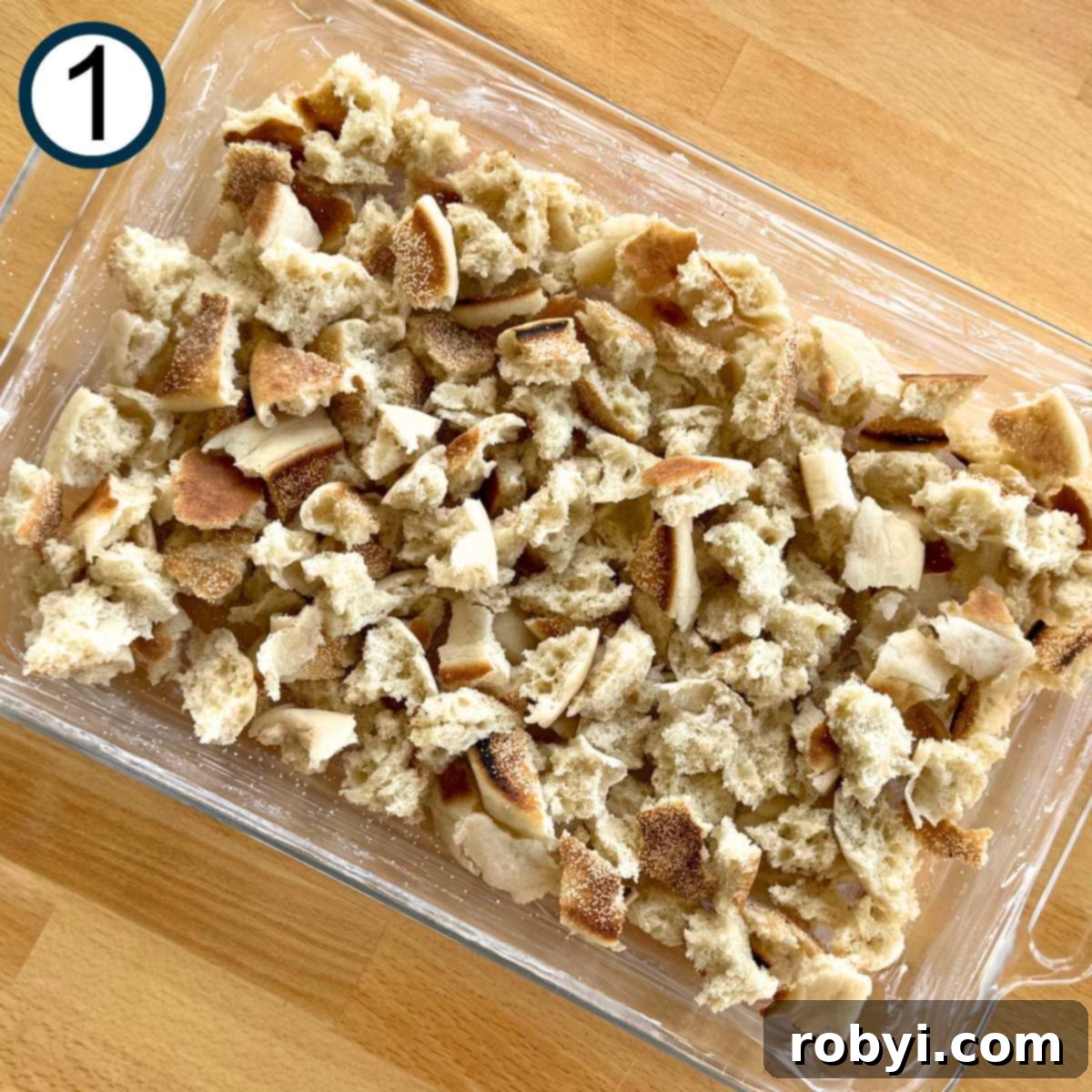 Bite-sized pieces of the English muffins in a large glass baking dish.