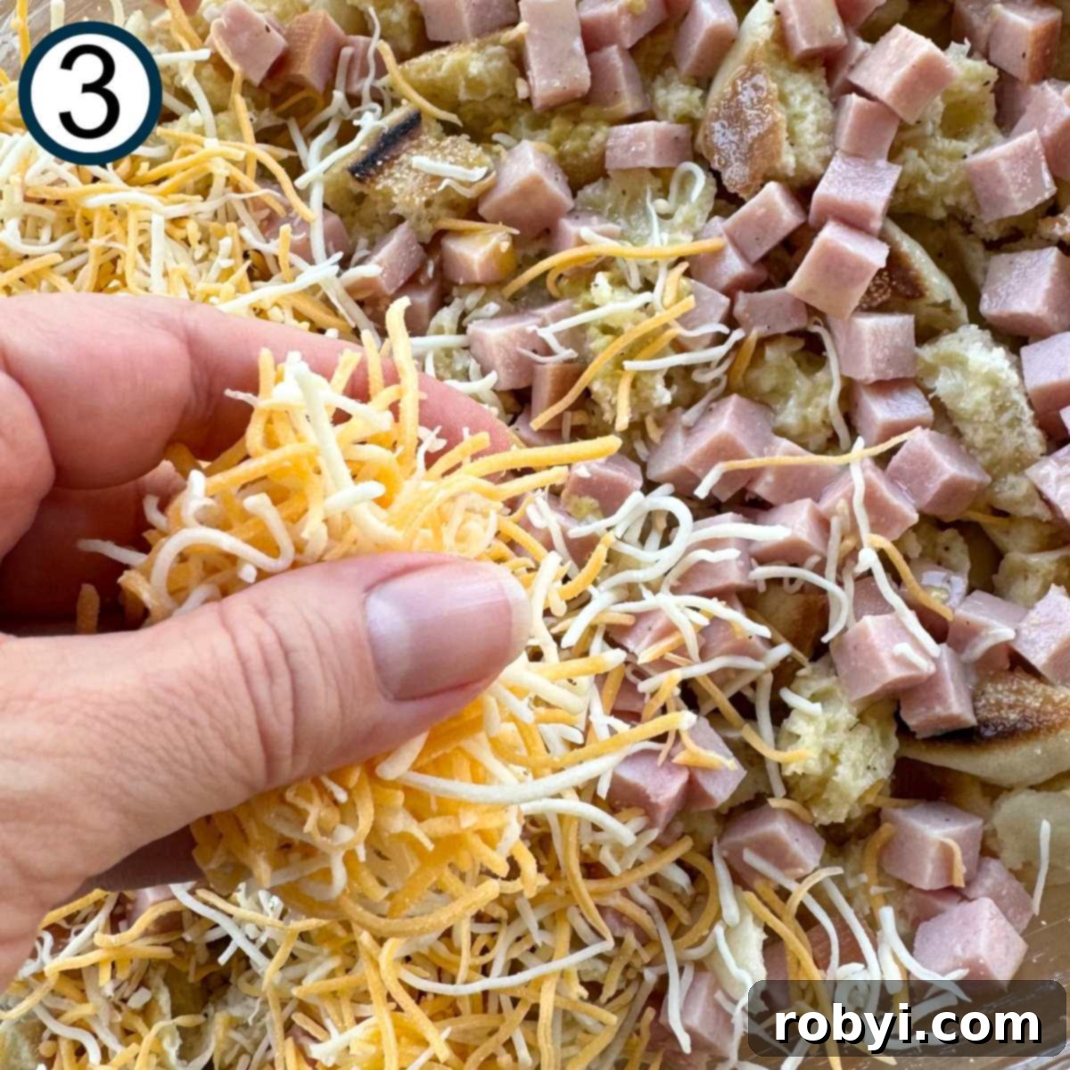 Hand sprinkling shredded Cheddar Jack cheese over the top of the layered casserole.