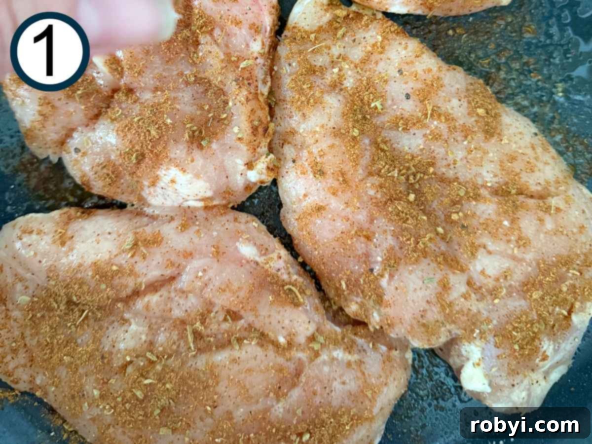 Chuckwagon Chicken Dinner 4 Seasoning being added to boneless skinless chicken breasts on a cutting board.