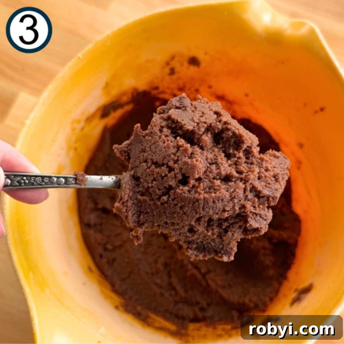 Decadent Zucchini Chocolate Brownies 6 A spoon holds a spoonful of thick, creamy brownie batter, showcasing the perfectly blended wet and dry ingredients.
