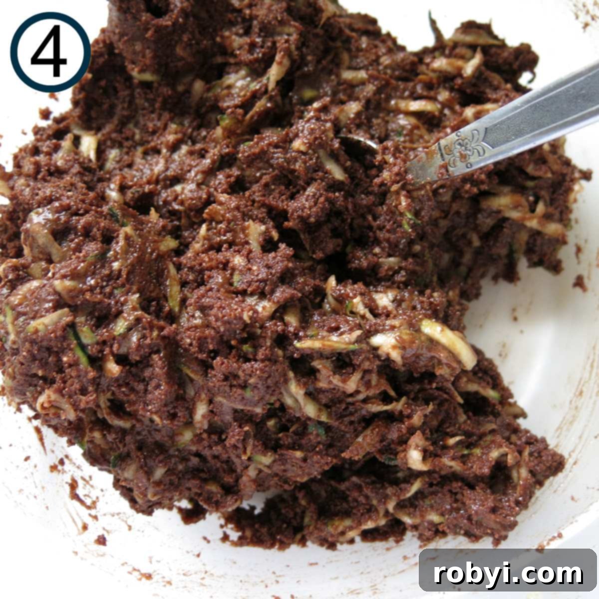 Decadent Zucchini Chocolate Brownies 7 A close-up shot of rich, dark chocolate brownie batter after the grated zucchini has been folded in, showing tiny green flecks.