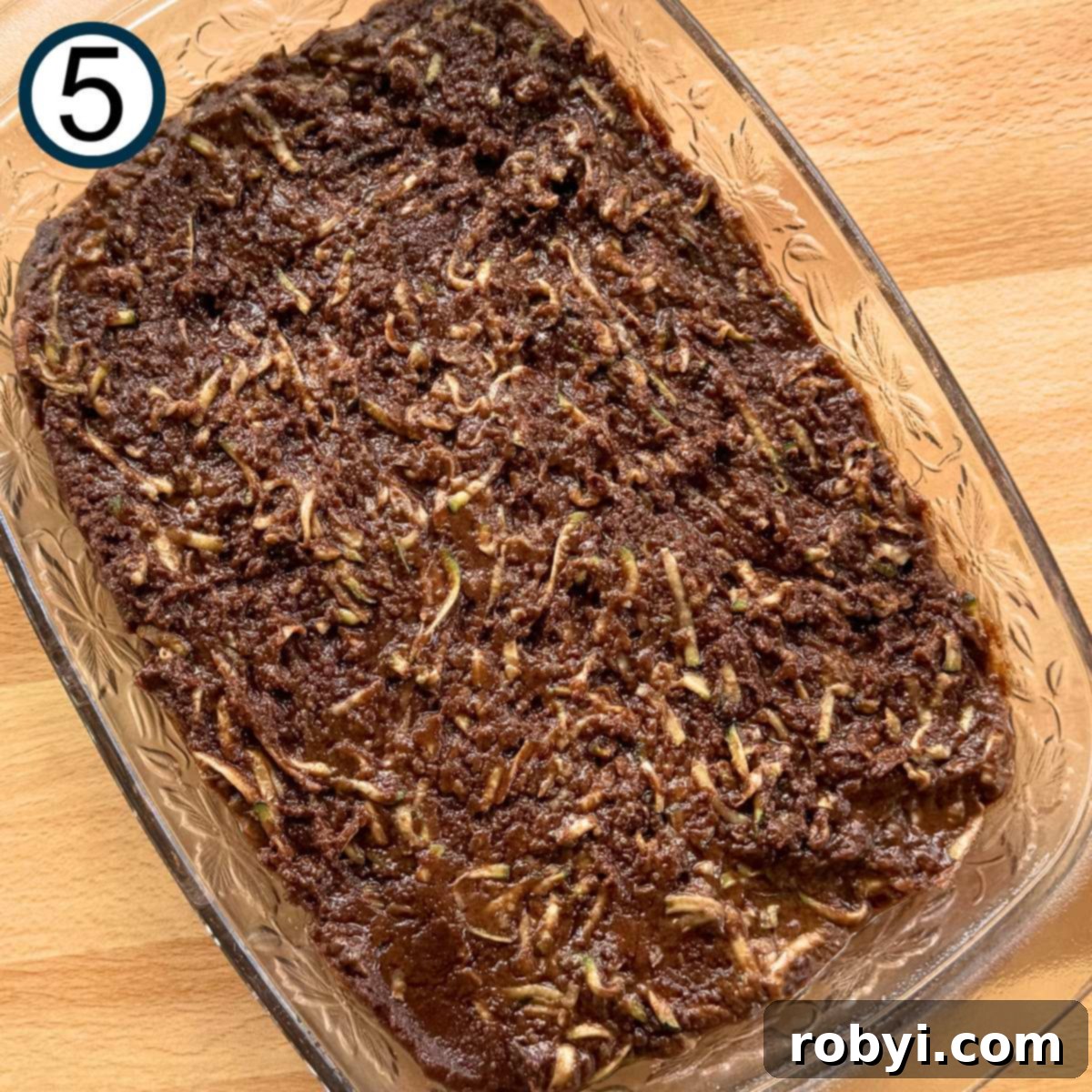 Decadent Zucchini Chocolate Brownies 8 The uncooked zucchini brownie batter is smoothly spread into a glass baking dish, lightly coated with nonstick spray.