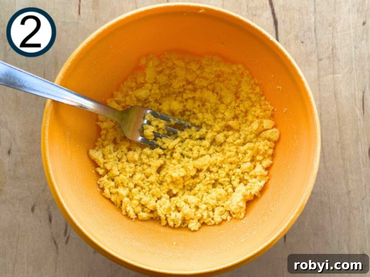 Bright and Light Egg Salad 5 Crumbled egg yolks in a small bowl with a fork.