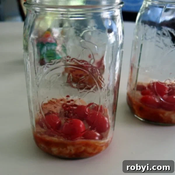 Build the Perfect Layered Taco Salad Jar: Prep & Packing Hacks 3 Close-up of dressing and grape tomatoes layered at the bottom of a mason jar, ready for the next ingredients.