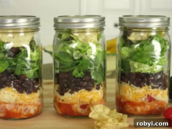 Build the Perfect Layered Taco Salad Jar: Prep & Packing Hacks 4 Three full layered taco salads in mason jars lined up, showcasing the successful meal prep.