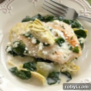 Serving of spinach artichoke chicken with a lemon cream sauce on a plate.