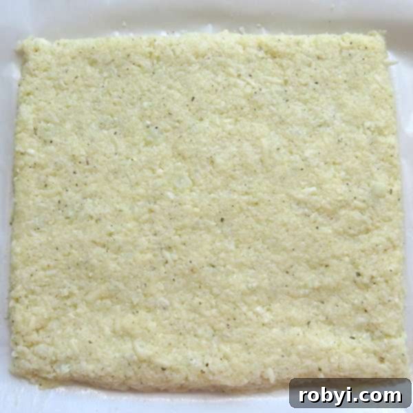 Healthy Cauliflower Pizza: Bites or Crispy Crust 7 Cauliflower pizza dough rolled flat into a rectangular shape on a baking sheet.