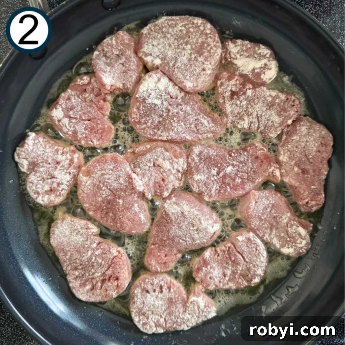 Pork medallions in a black skillet with butter and olive oil.