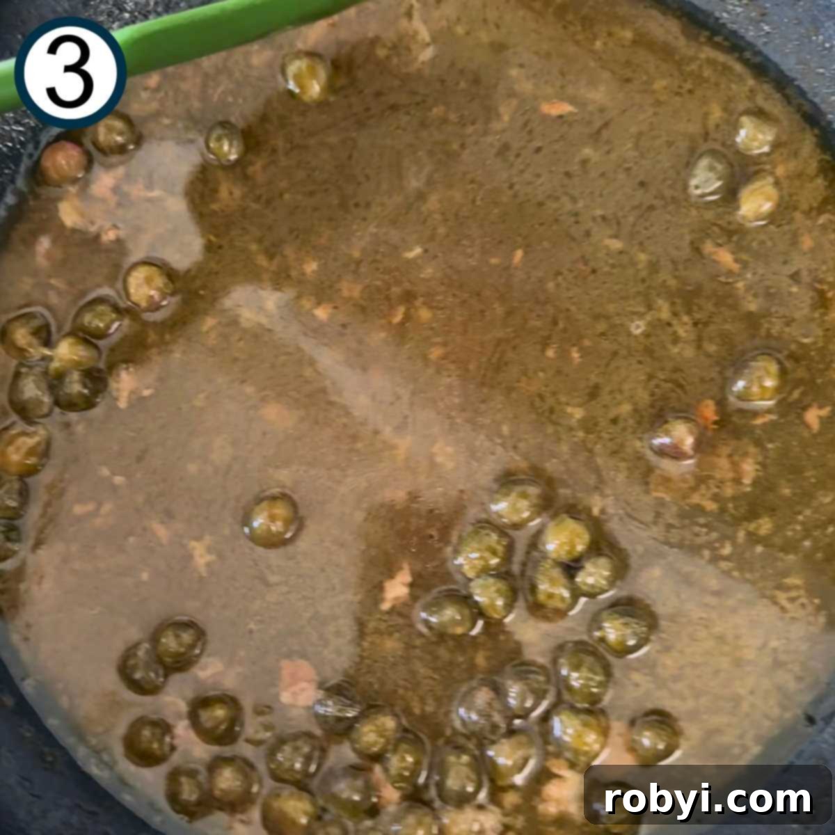 Chicken broth, lemon juice, melted butter, and capers in the skillet after it has thickened.