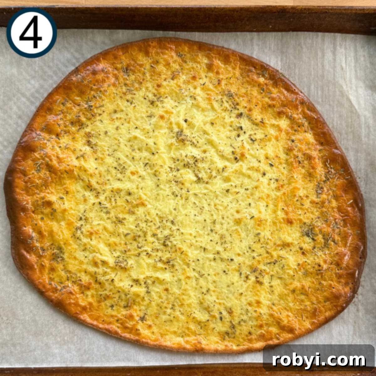 Baked cottage cheese flatbread on a parchment paper, with slightly browned edges.
