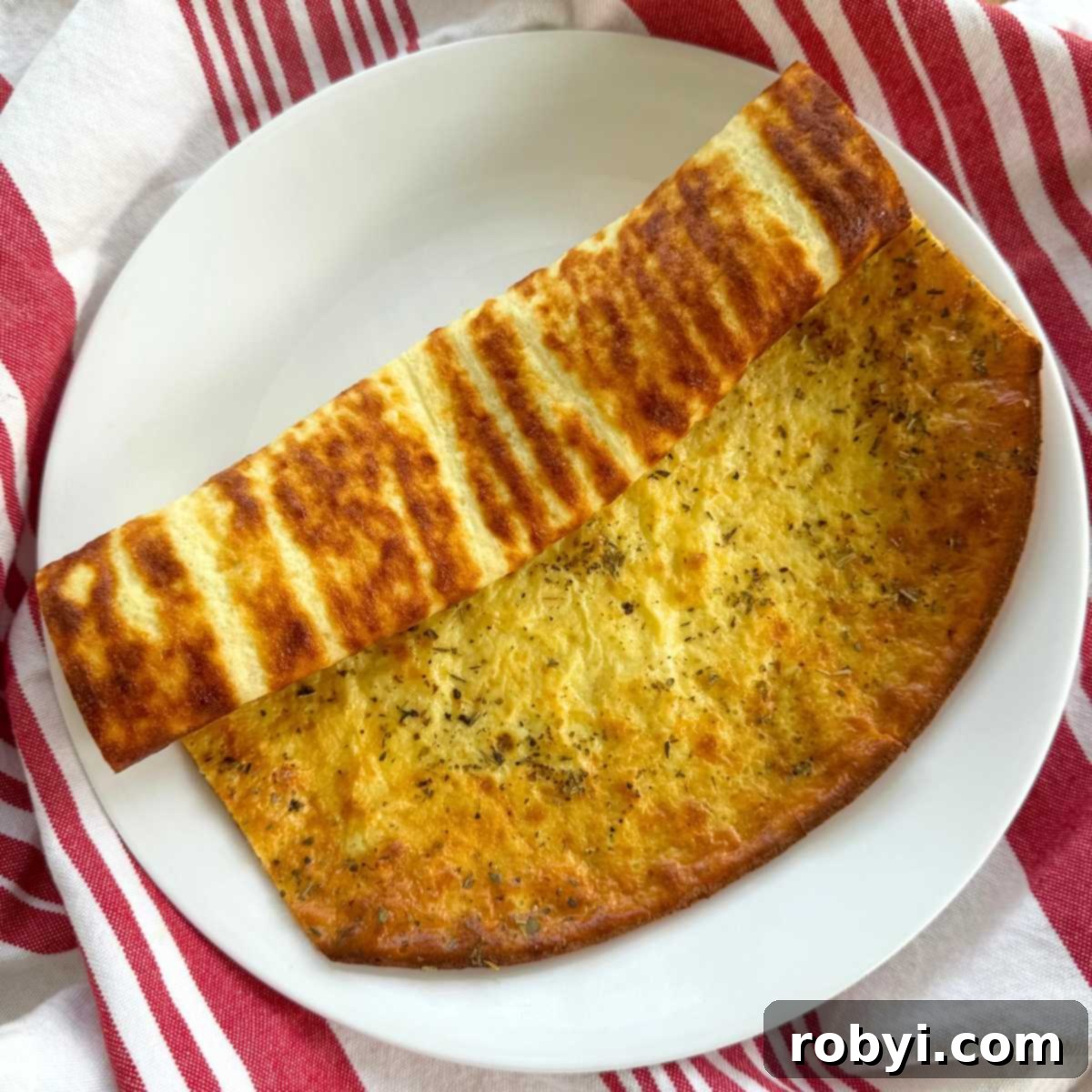 Cottage cheese flatbread ,with long sides trimmed, partially rolled on a white plate.