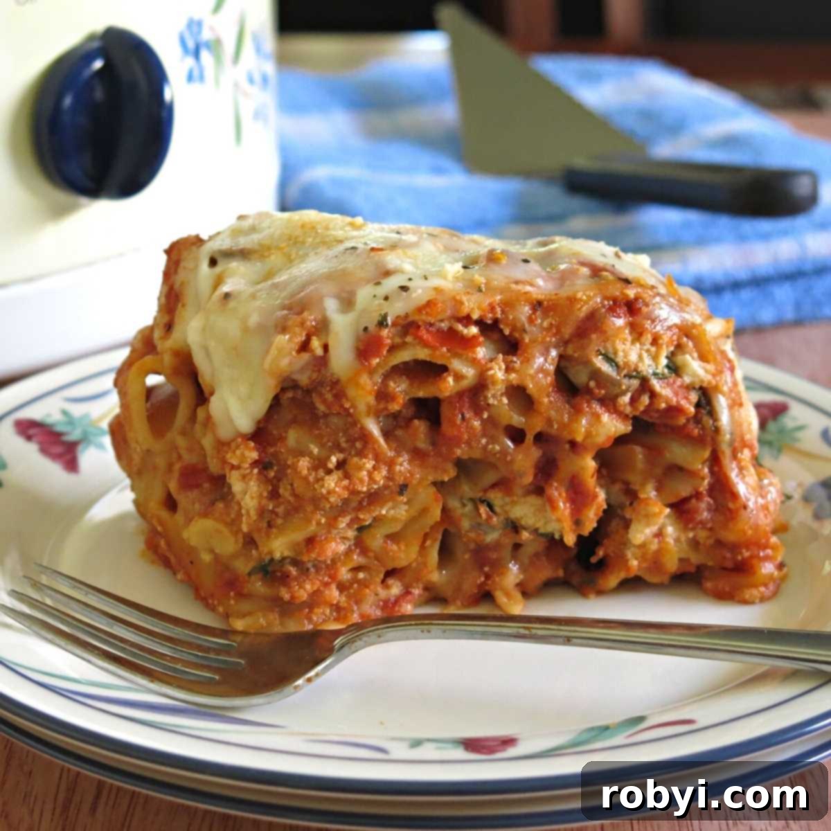 Serving of Crock-Pot Baked Ziti with ricotta in front of a slow cooker, showcasing its creamy layers.