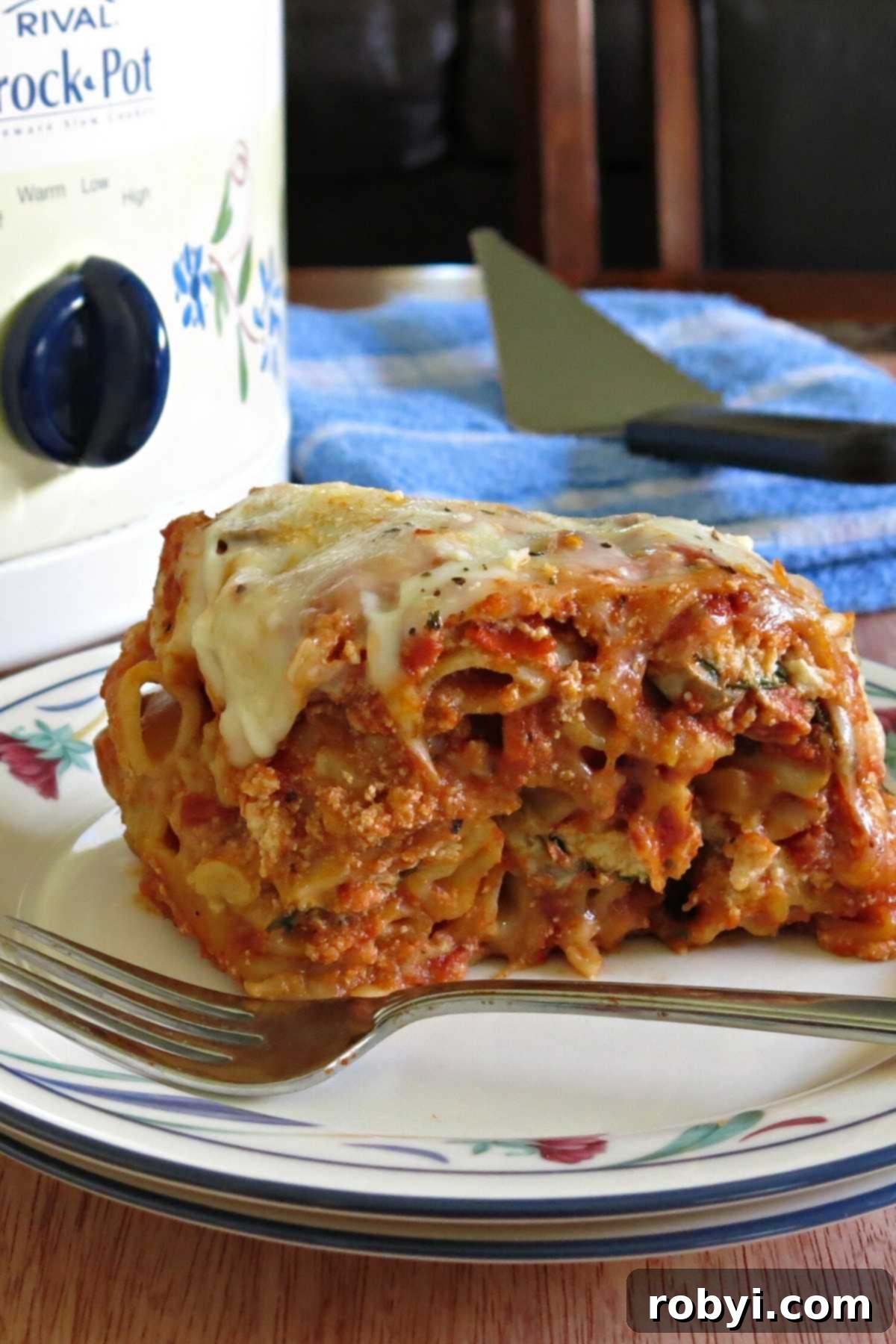 Serving of slow cooker baked ziti with the crock-pot visible in the background, ready for a cozy meal.