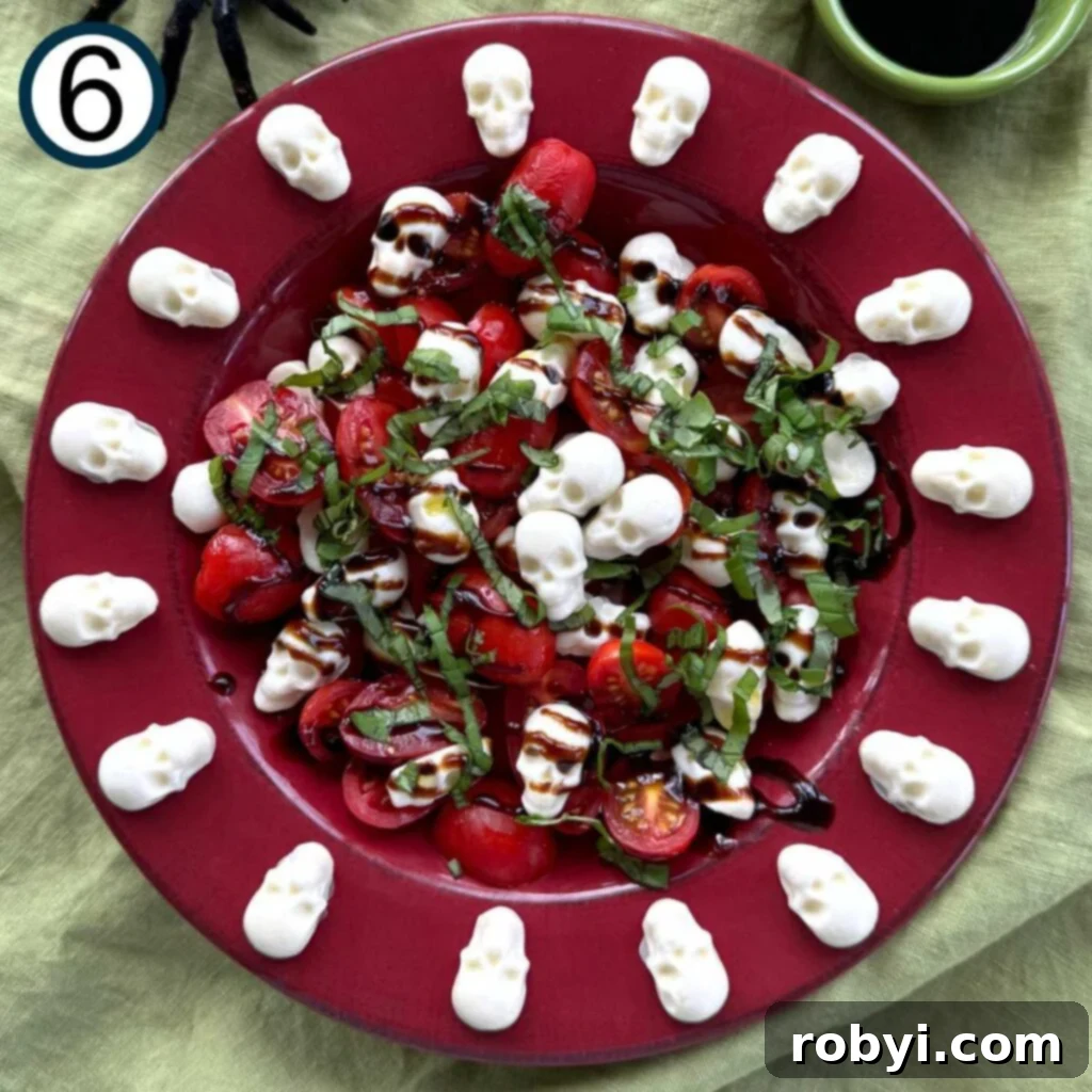 A vibrant red bowl filled with sliced tomatoes and mozzarella skulls, generously drizzled with balsamic glaze and garnished with freshly chopped basil.