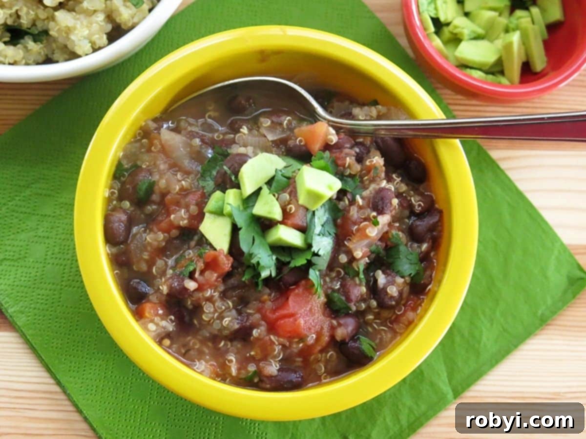 A vibrant yellow bowl filled with hearty black bean quinoa soup, artfully placed on a textured green napkin, highlighting its rich color.