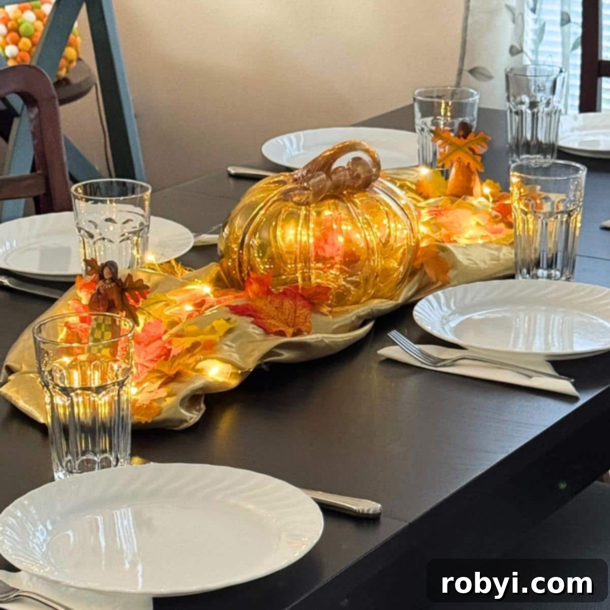 Host a Friendsgiving Feast for Less 2 Friendsgiving tablescape with a pumpkin, fall leaves, elegant plates, festive napkins, and sparkling glasses, creating a warm and inviting atmosphere.