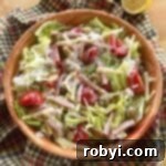 Host a Friendsgiving Feast for Less 7 Columbia 1905 Salad with ham, cheese, green olives, and tomatoes and garlic vinaigrette dressing in a bowl.