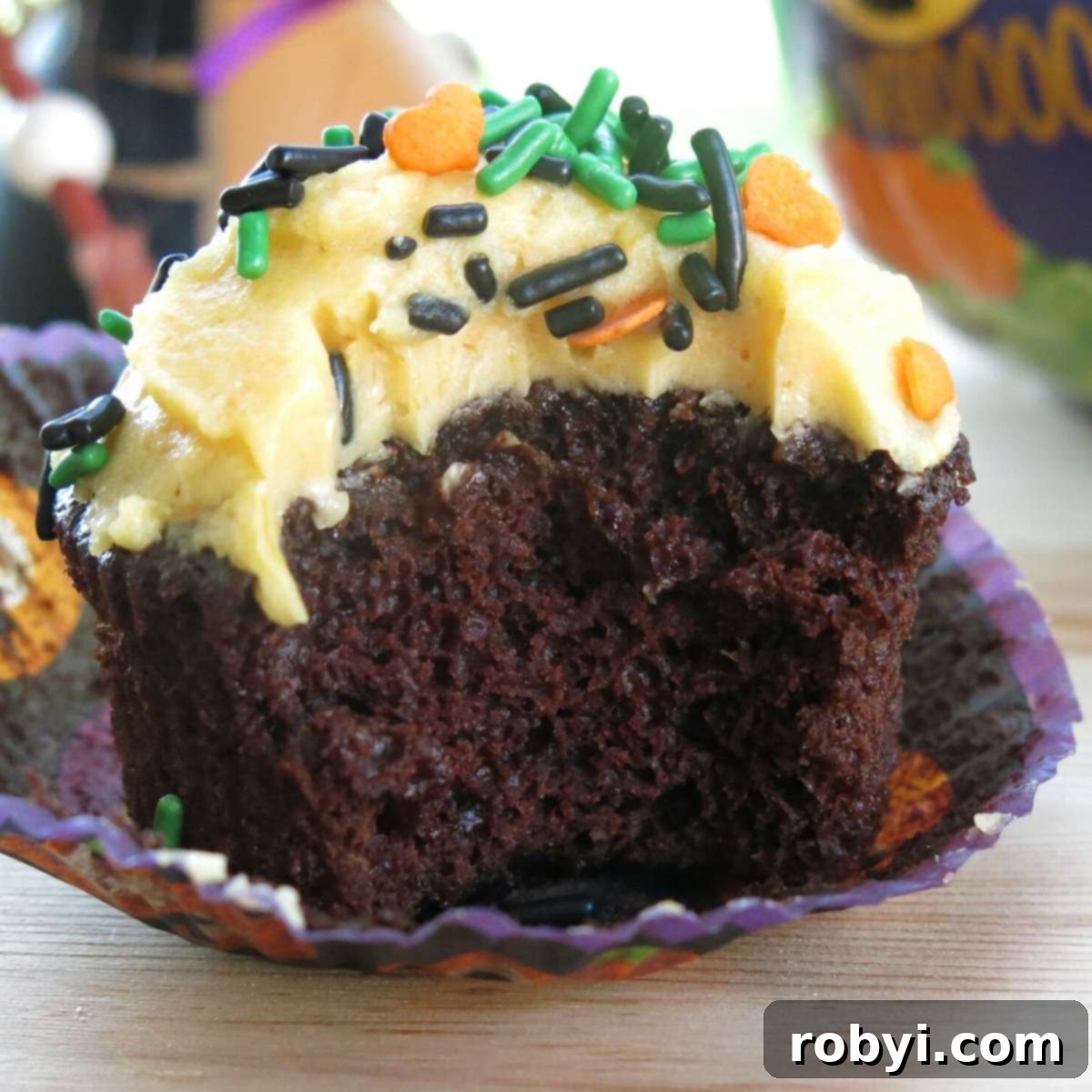 Wacky chocolate pumpkin cupcake with a bite removed to expose the moist inside cake.