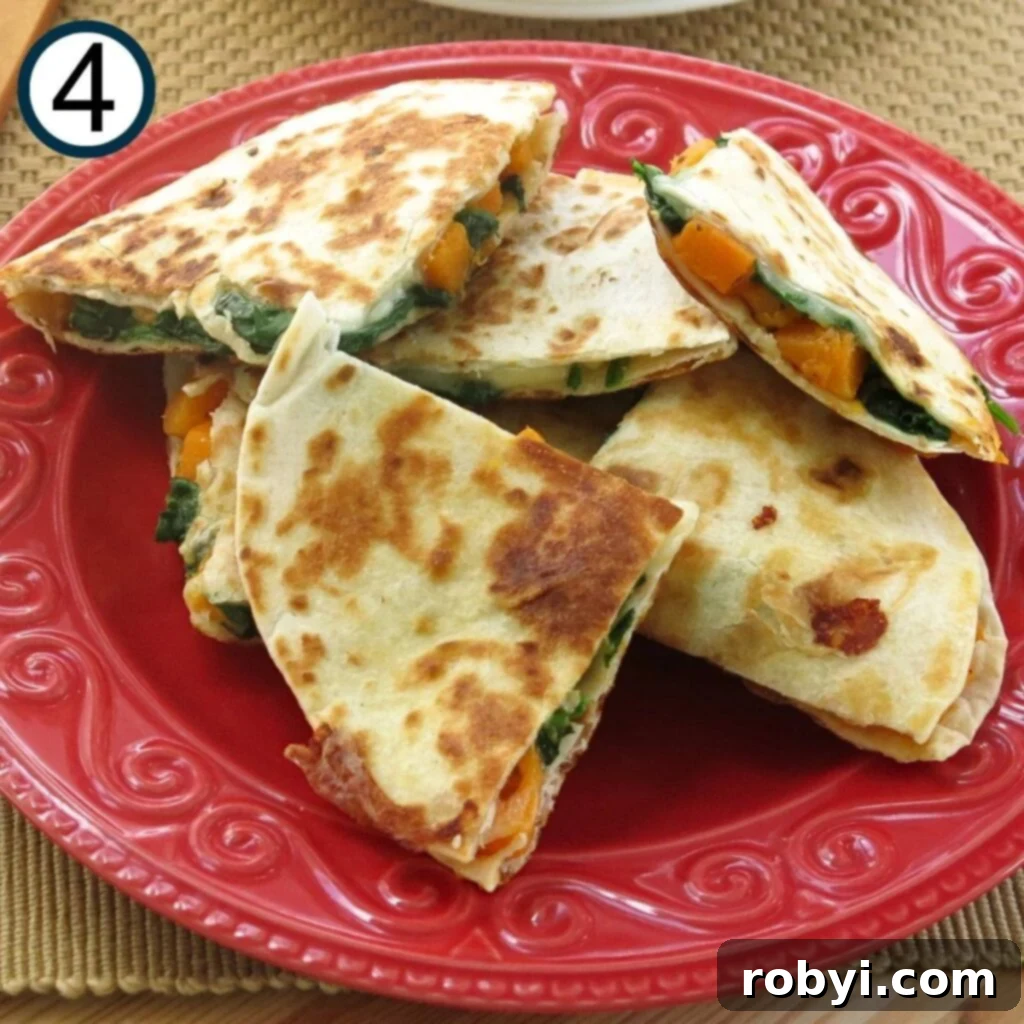 A cooked butternut squash quesadilla being carefully flipped in a skillet with a large spatula, revealing a perfectly browned underside.