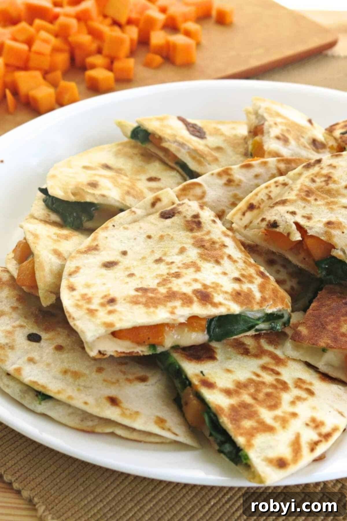 A beautifully presented plate of butternut squash, spinach, and cheese quesadillas, garnished with fresh cilantro, ready to be enjoyed.