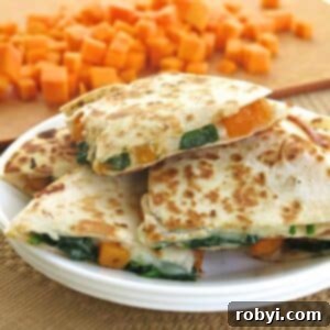 Butternut squash quesadillas cut into triangles on a plate with cubes of butternut squash in the background.