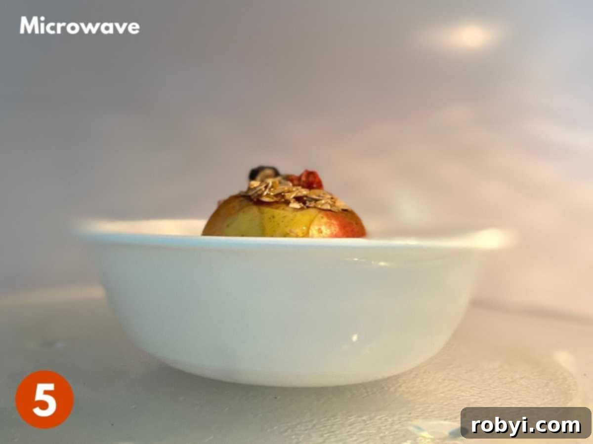 Warm Apples in Minutes 4 A white bowl with a cooked apple, generously topped with granola, after microwaving.