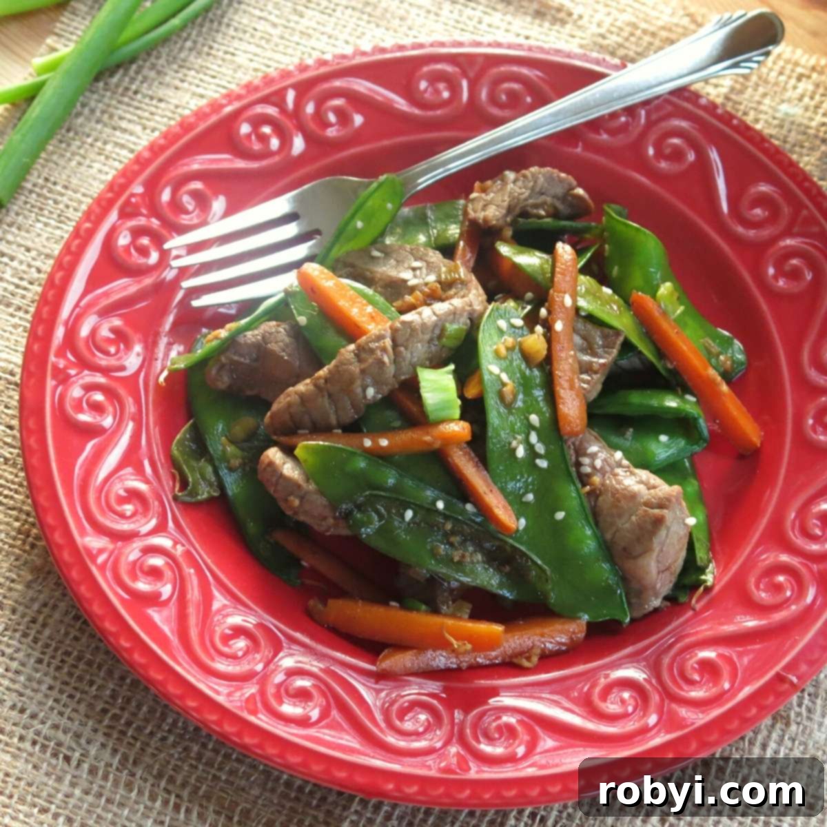 Sesame beef stir fry on plate with fork,