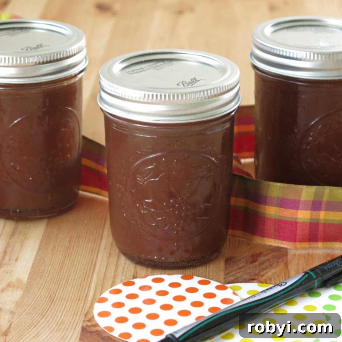 Naturally Sweet Slow Cooker Apple Butter 5 Three decorated mason jars filled with homemade sugar-free apple butter, surrounded by gift tags and ribbon, ready for gifting.