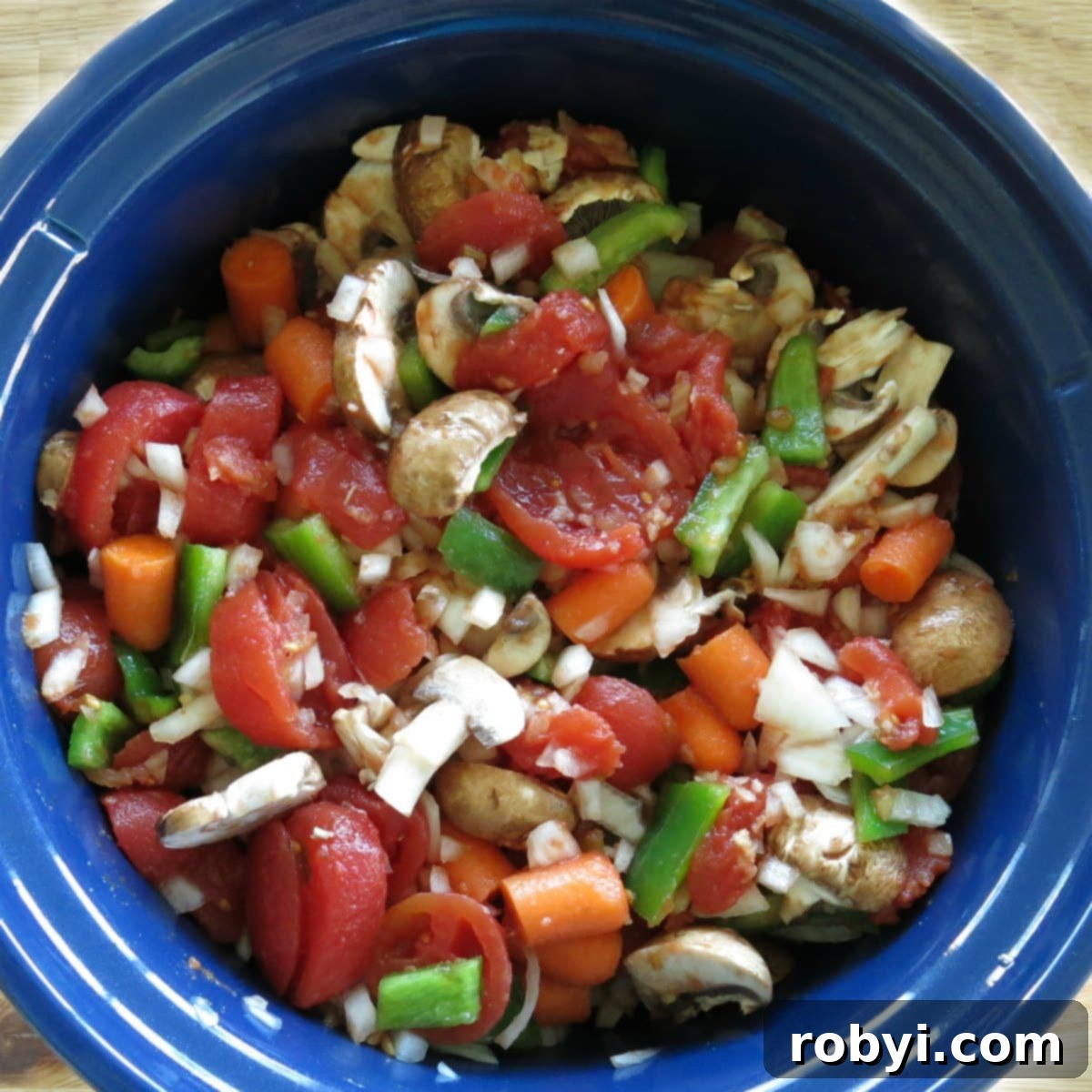 Slow cooker filled with colorful vegetables, rich stewed tomatoes, and tender chicken.