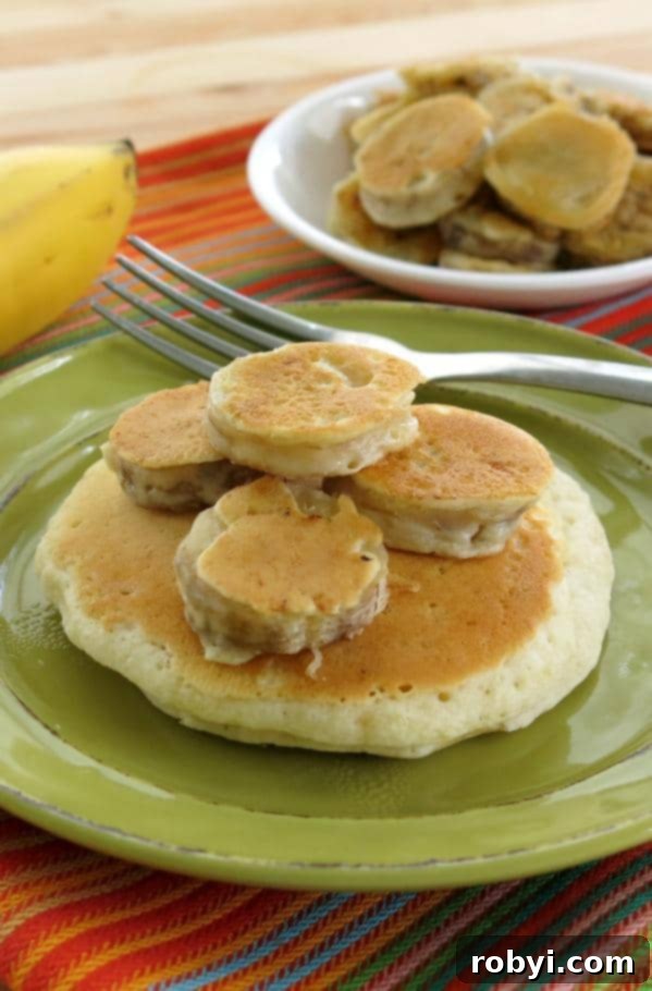 Sweet Fluffy Banana Pancakes 5 A large pancake topped with several golden-brown battered banana medallions and a fork, invitingly presented.
