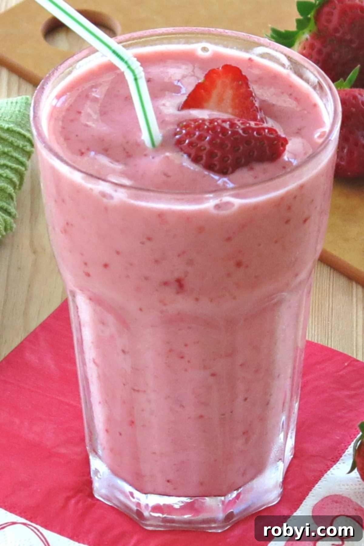 Refreshing Strawberry Yogurt Delight 3 Easy strawberry smoothie with yogurt and ice in a tall glass with a straw, garnished with a fresh strawberry.