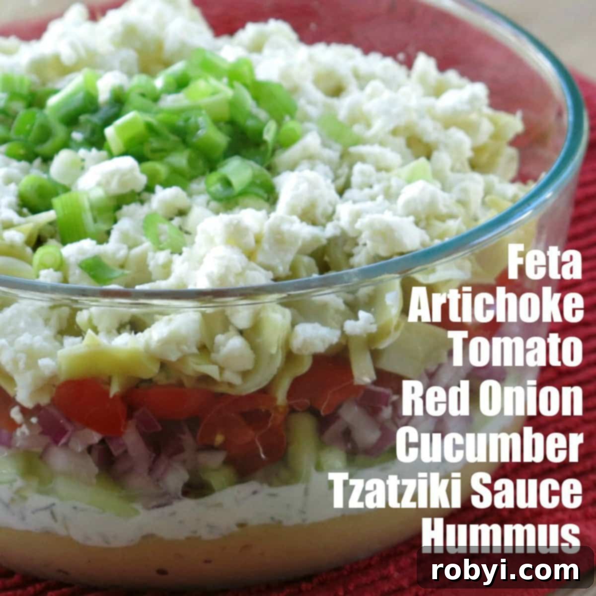 Greek Layer Dip in glass bowl with layers labeled.