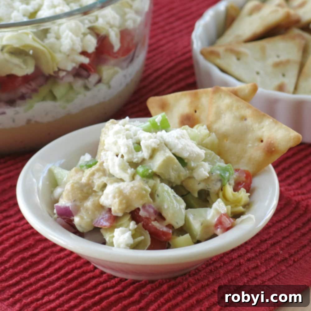 Serving of Greek dip in a small bowl with two crackers on the side.