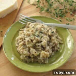 Cheesy mushroom quinoa on a plate with Parmesan cheese and thyme in the background.