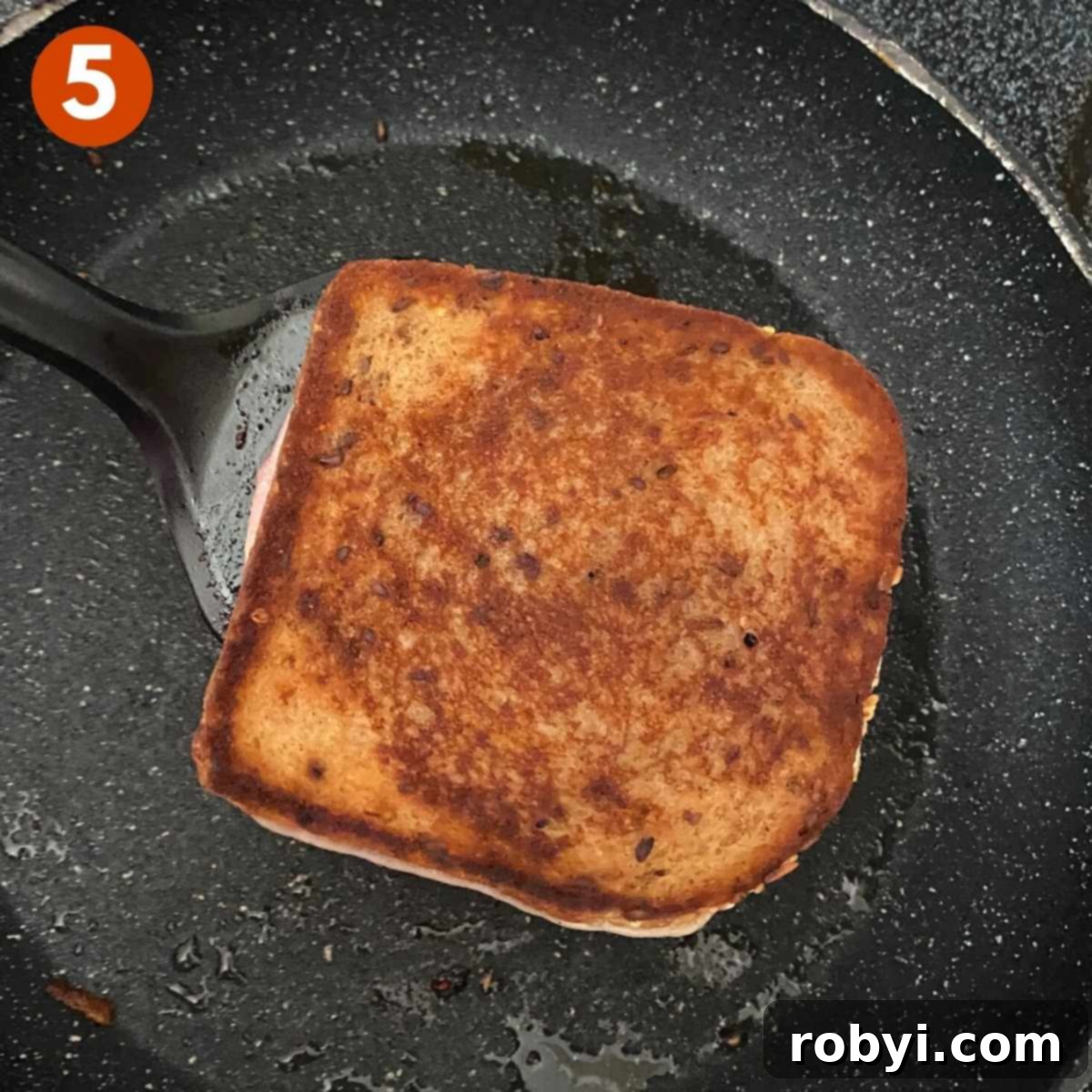 Monte Cristo Grilled Cheese: Sweet, Savory, and Jam-Stuffed 4 A perfectly grilled Monte Cristo sandwich on a spatula, just removed from the pan, showing its golden-brown crust and melted cheese within.