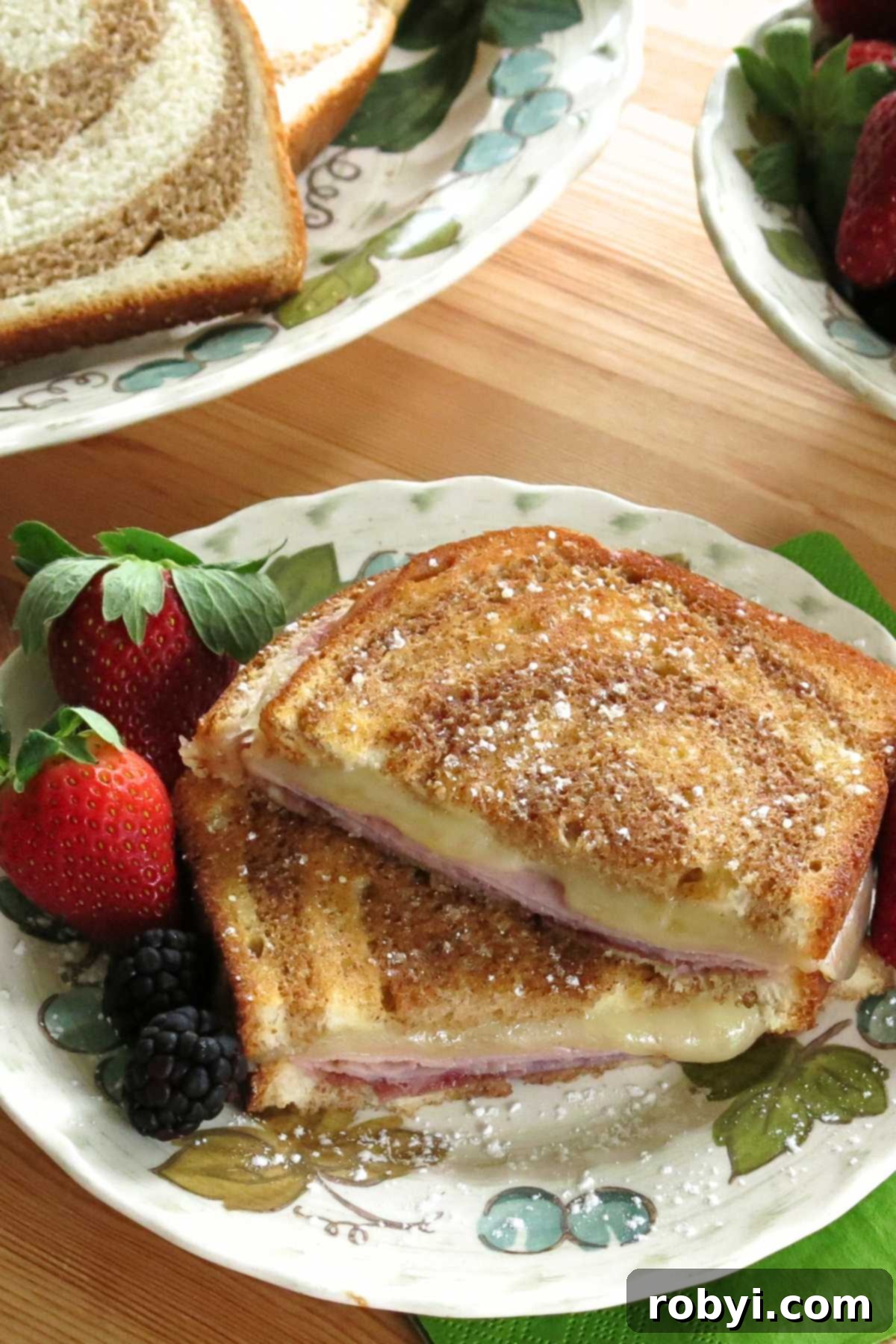 Monte Cristo Grilled Cheese: Sweet, Savory, and Jam-Stuffed 5 Monte Cristo grilled cheese sprinkled with powdered sugar on a plate with fresh strawberries and blackberries, ready to serve.