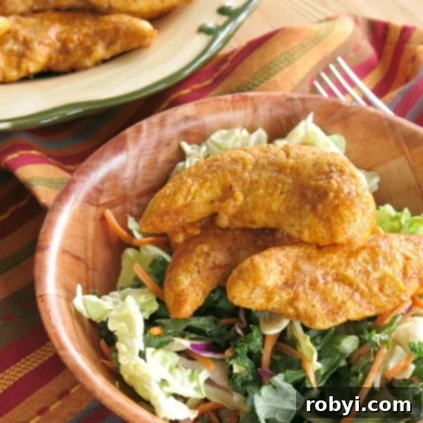 Parmesan Paprika Chicken tenders served over a bed of fresh salad greens in a bowl.