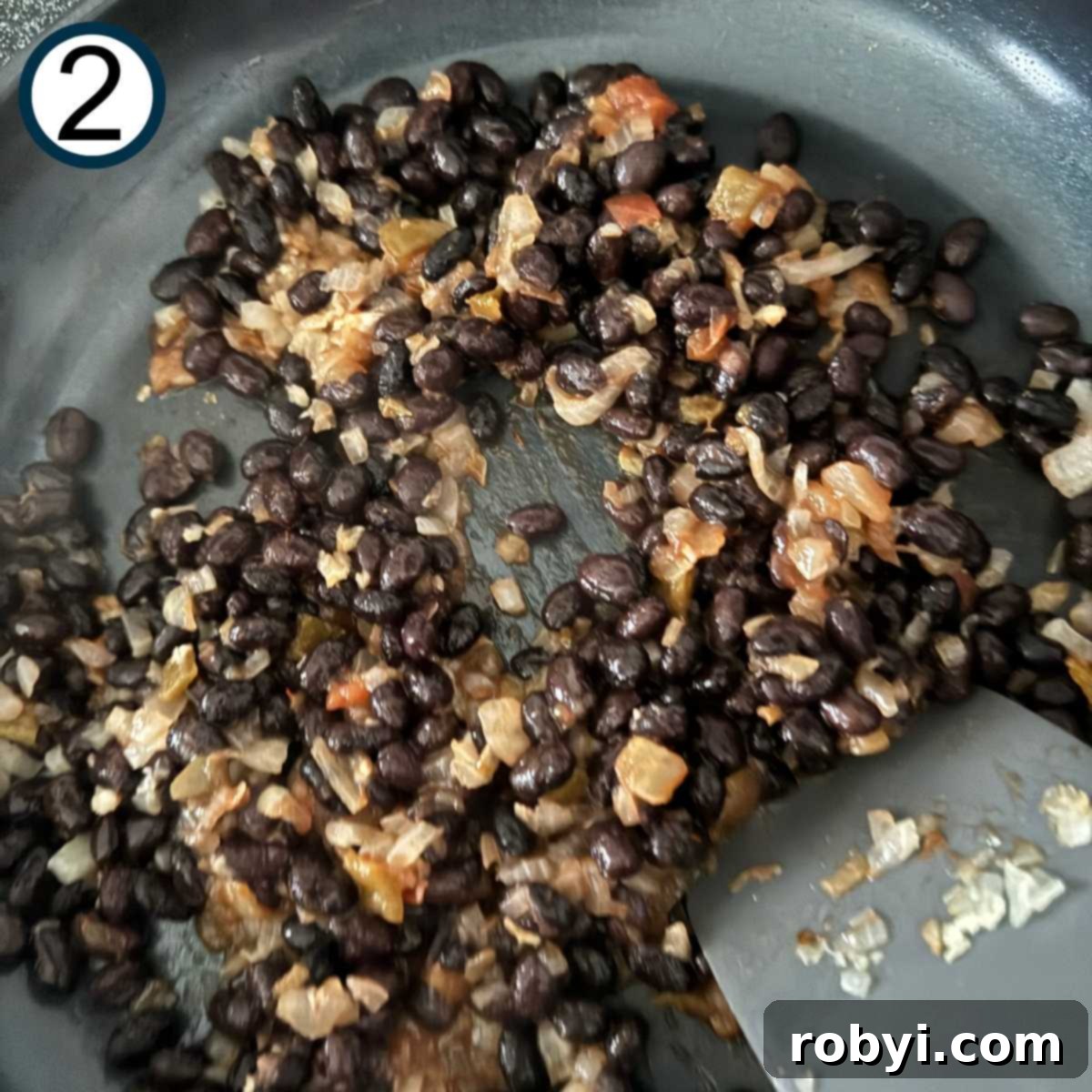 Black beans, sautéed onion, garlic, and salsa combined in a skillet.