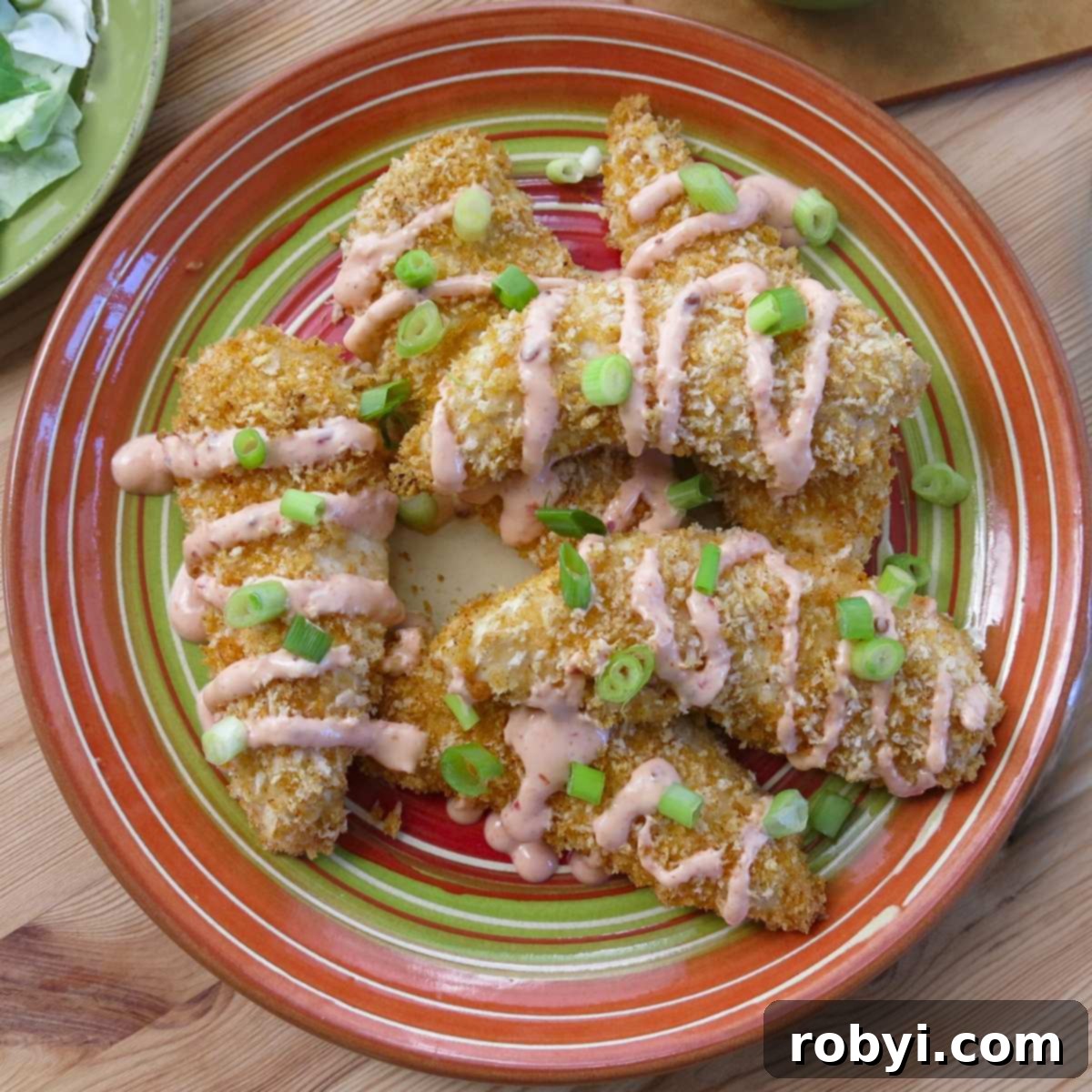 Healthy Baked Bang Bang Chicken drizzled with bang bang sauce made with yogurt on a plate.