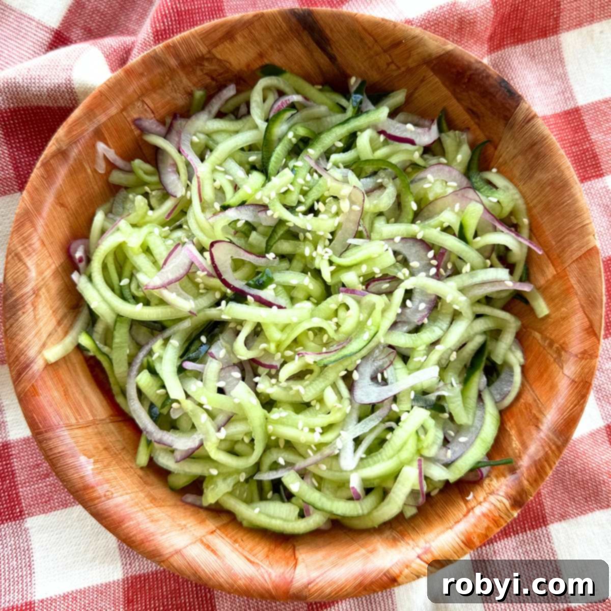 Easy cucumber salad with rice vinegar, red onion and sesame seeds in a brown bowl.