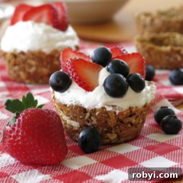 No-Bake Mini Cheesecakes in Pretzel Crust Cups topped with blueberries and strawberries, a perfect patriotic dessert