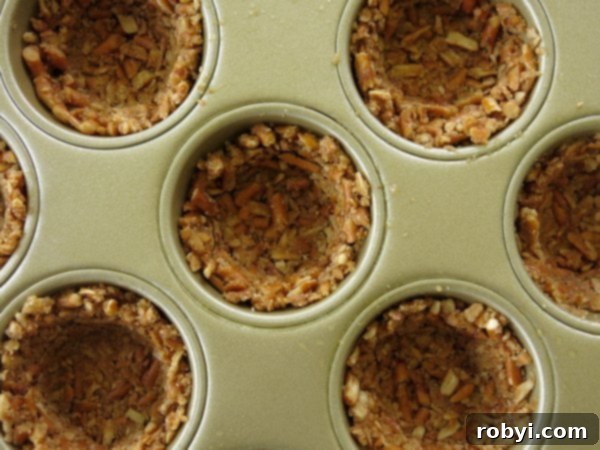 Pretzel crusts pressed into a muffin tip to make cups, ready for baking and filling