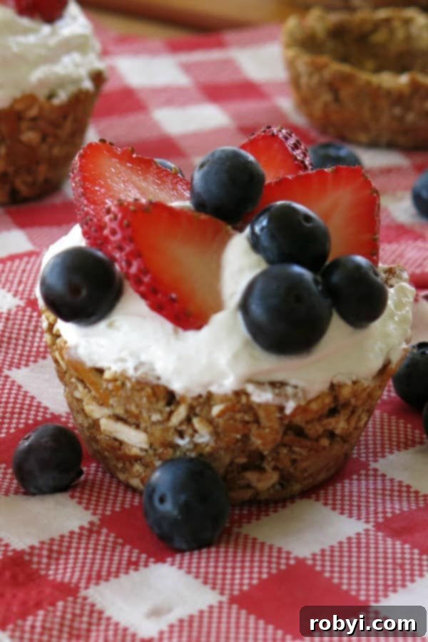 No-Bake Mini Cheesecakes topped with blueberries and strawberries in pretzel crust cup, a delicious and easy dessert idea
